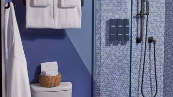 A modern bathroom with a white toilet, a glass-enclosed shower, and a blue tiled floor.