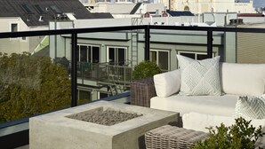 A rooftop terrace with a white sofa, a concrete planter, and a view of the cityscape including a building with a distinctive facade. - The Hotel Castro San Francisco (San Francisco)