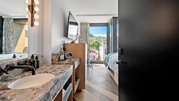 A modern bathroom with a large mirror, vanity with a sink, and a flat-screen TV. - The Hotel Castro San Francisco (San Francisco)