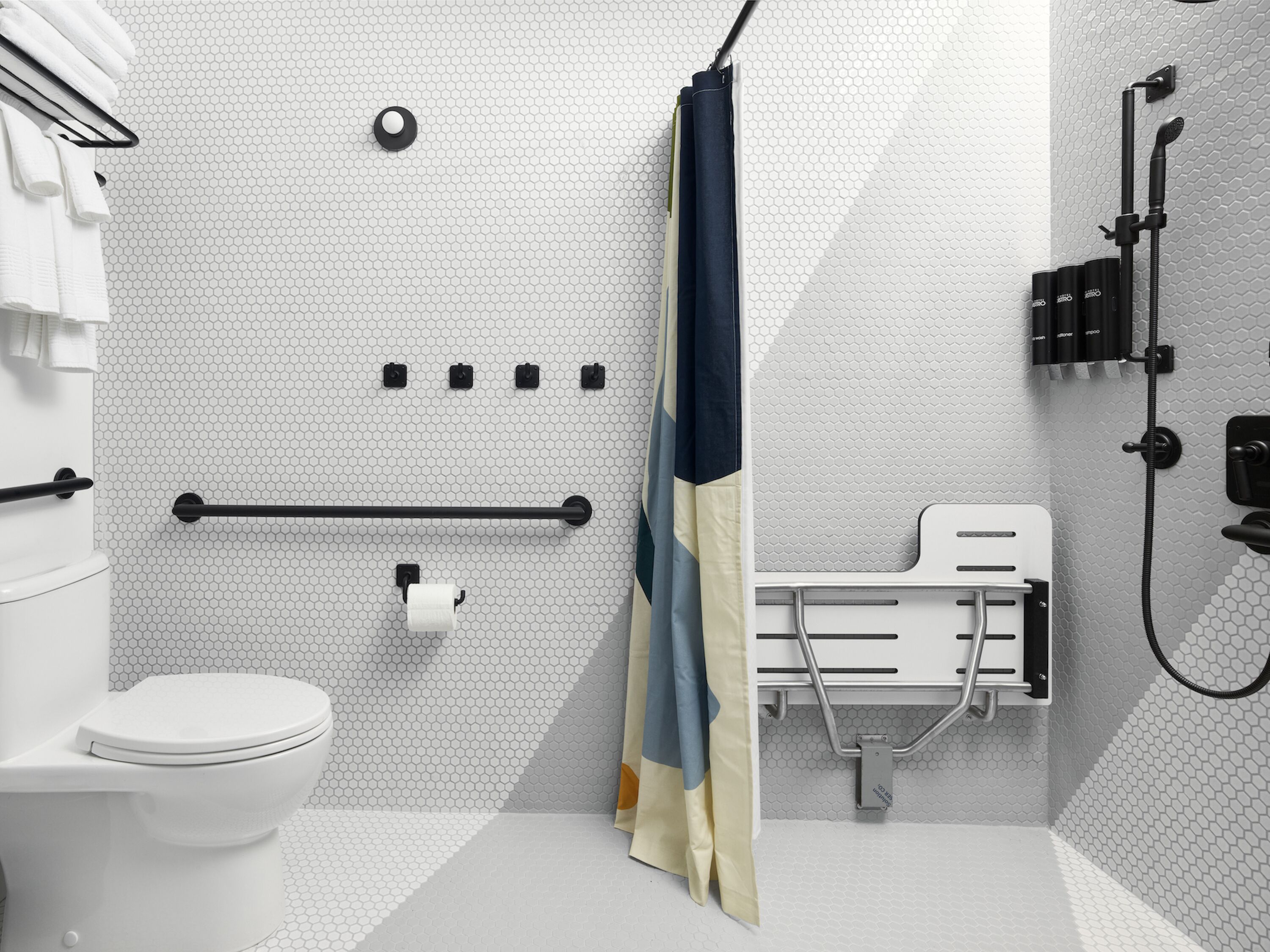 A modern bathroom with a toilet, towel rack, shower, and a hand dryer.