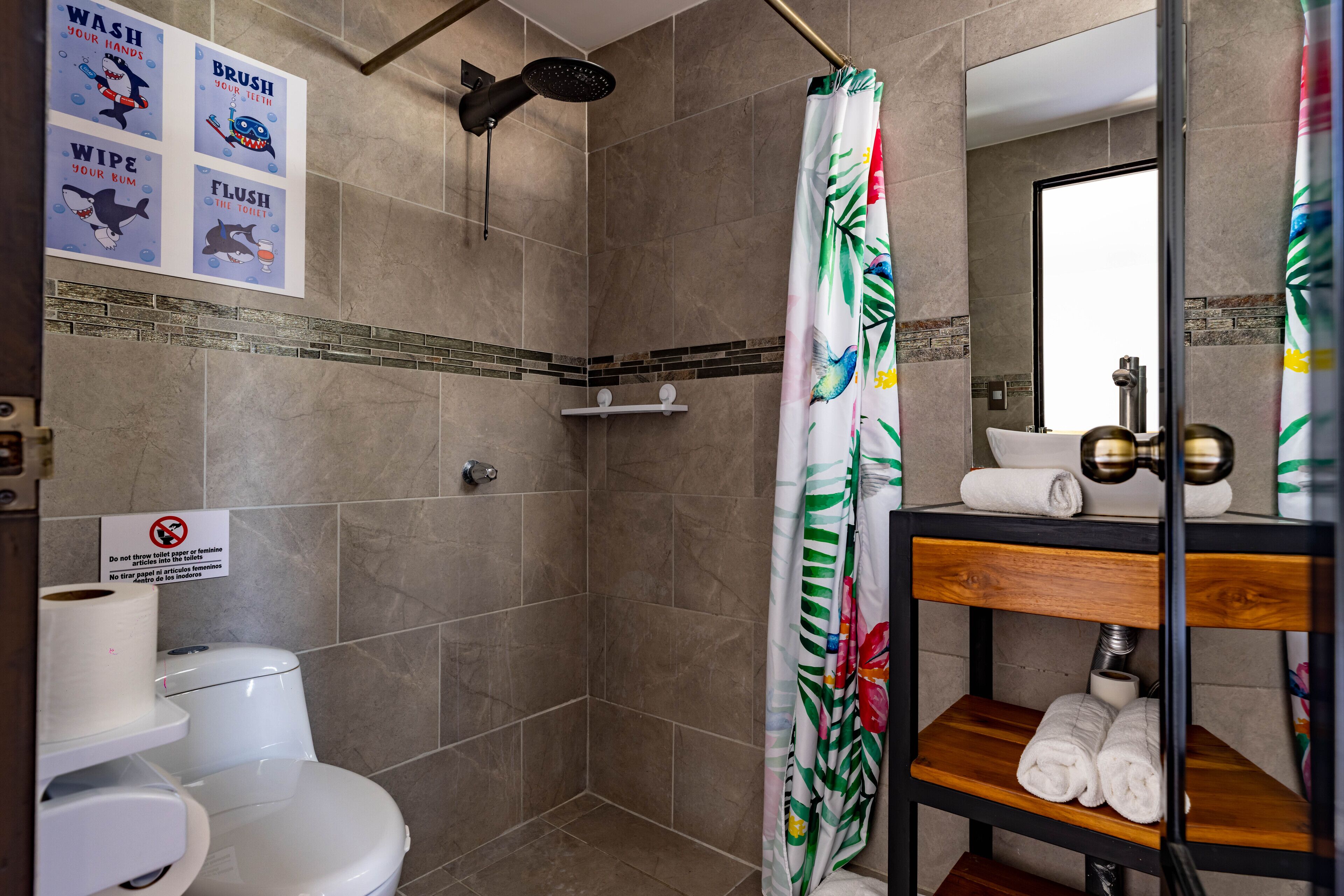 A bathroom with a shower, toilet, and a shelf with towels.