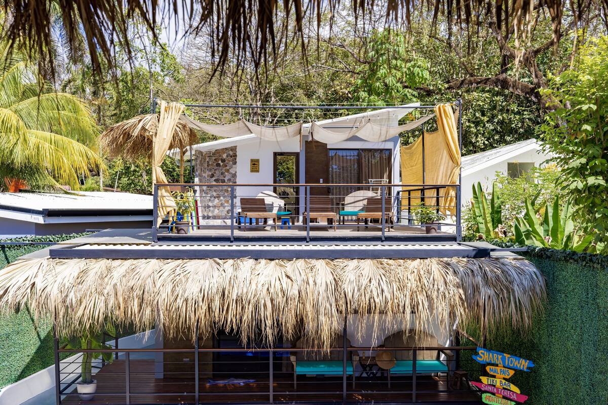 A thatched-roof structure with outdoor seating and a sign indicating nearby attractions.