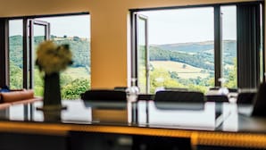Habitación de hotel con vistas a colinas ondulantes y un florero en el alféizar de la ventana.