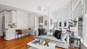A modern living room with a sofa, coffee table, and dining area. - The Iris Charleston (Charleston)