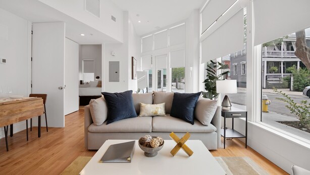 A modern living room with a sofa, coffee table, and a view of the street. - The Iris Charleston (Charleston)