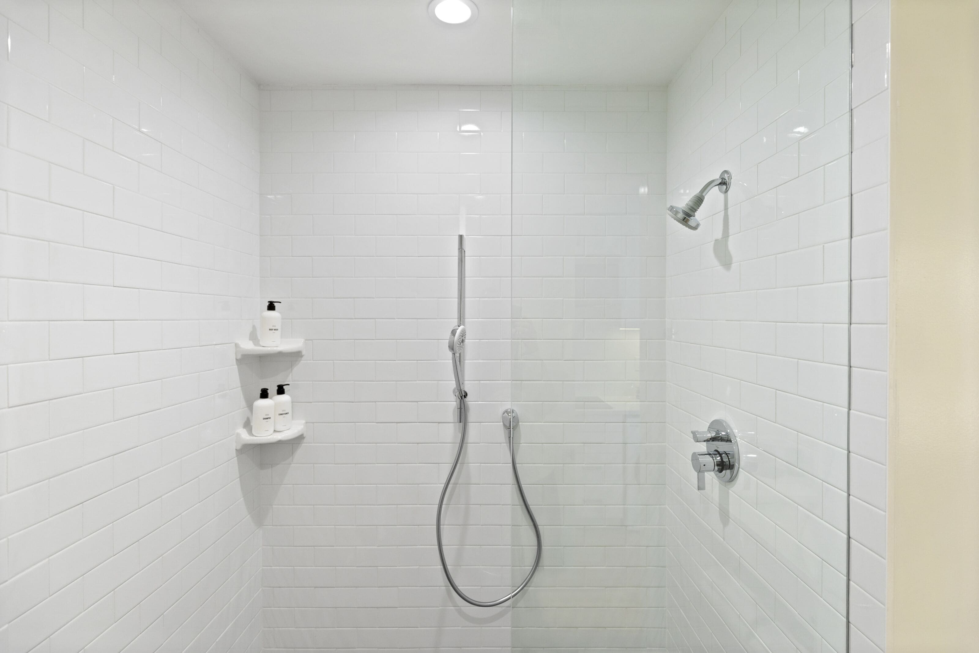 A modern shower with a handheld showerhead and a wall-mounted faucet.