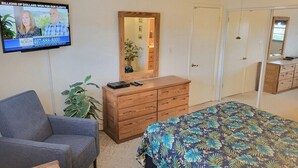 A bedroom with a bed, a dresser, a television, and a chair. - 108 - 2 BR Poolside Great View (New Smyrna Beach)