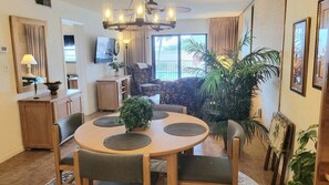 A dining area with a round table, chairs, and a chandelier. - 108 - 2 BR Poolside Great View (New Smyrna Beach)