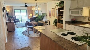 A modern kitchen with a central island, a dining area with a round table, and a living room with a sofa and a coffee table.