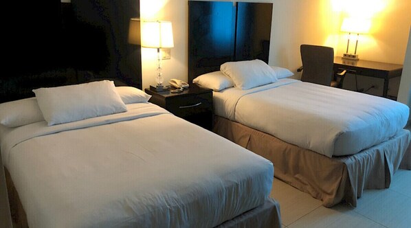 A hotel room with two beds, bedside tables, lamps, and a desk with a chair. - Studio Coliving Double Room (Panama)