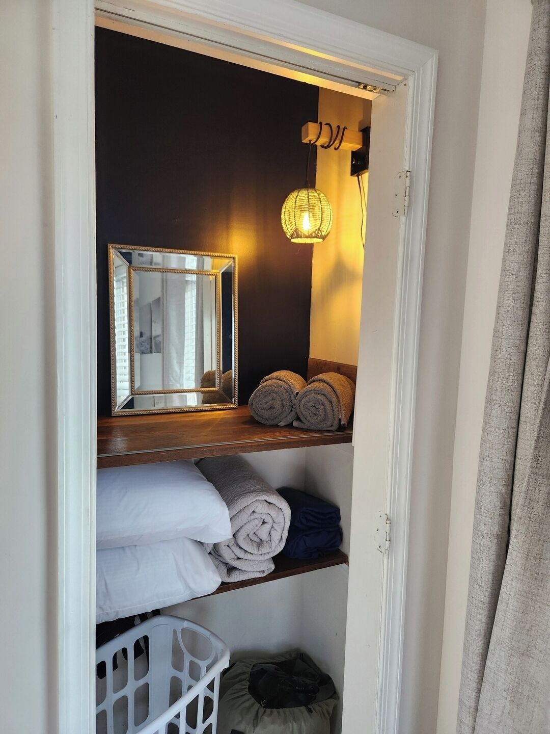 Une chambre d’hôtel avec un miroir, un luminaire suspendu et des serviettes soigneusement pliées sur une étagère.