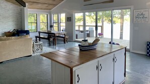Ein geräumiges Wohnzimmer mit Holzbalkendecke, großen Fenstern, einem Esstisch und einer gemütlichen Sitzecke.