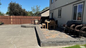 A backyard patio with a concrete floor, a wooden fence, and outdoor furniture including chairs and a table. - Group Fun - 7 Separated Sleeping Areas! (Redmond)
