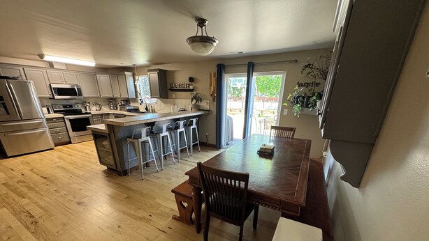 A modern kitchen with stainless steel appliances, a wooden dining table, and a bar area. - Group Fun - 7 Separated Sleeping Areas! (Redmond)