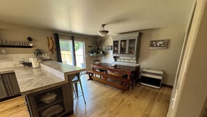 A kitchen with a wooden island, a dining table with chairs, a built-in oven, and a window with curtains. - Group Fun - 7 Separated Sleeping Areas! (Redmond)