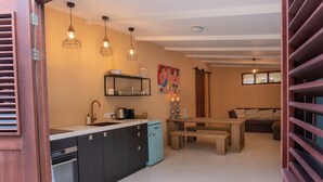 Une cuisine de taille réduite avec un réfrigérateur bleu, des armoires en bois et des luminaires suspendus.
