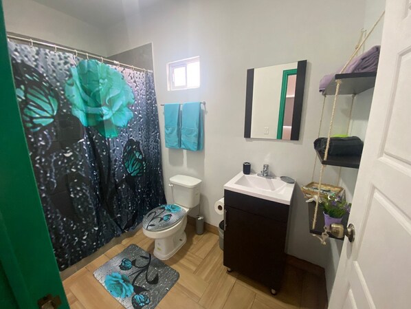 A bathroom with a toilet, sink, and a shower curtain with a floral design.