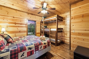 Habitación de cabaña de madera con literas, ventilador de techo, ventana y lámpara.