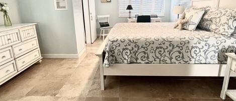A bedroom with a bed, dresser, chair, and a ceiling fan.
