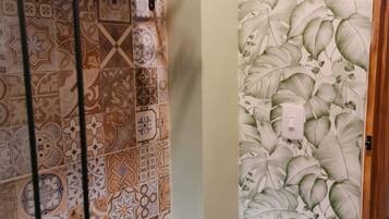 Un baño con baldosas estampadas, inodoro, toallero y cortina de ducha con diseño de hojas.