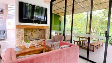 Un soggiorno moderno con un divano rosa, una TV a schermo piatto e una parete in pietra.