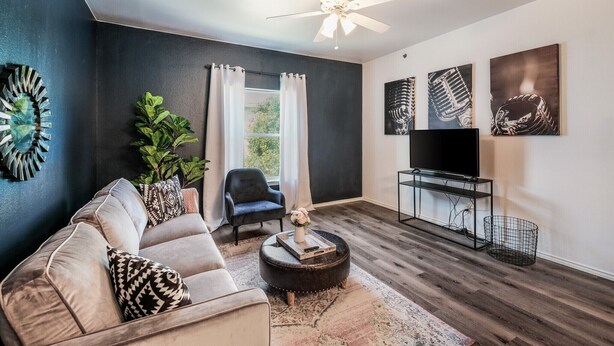 Una sala de estar moderna con un sofá, un reposapiés y un mueble para televisión.