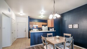 Una cocina moderna con armarios de madera, una isla central y un comedor con mesa y sillas de madera.
