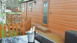 Une cabane en bois avec une terrasse et une cour clôturée.