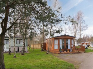 A wooden cabin with large windows, surrounded by trees and a grassy area. - 2 bedroom accommodation in Felton, near Morpeth (Felton, near Morpeth)