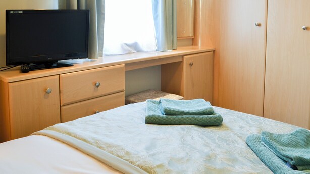 Une chambre à coucher avec un lit, un téléviseur posé sur un bureau et une armoire.