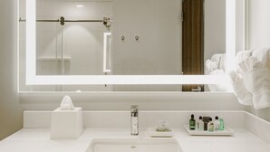 Een moderne badkamer met een wit wastafel, een grote spiegel met LED-verlichting en een handdoekhouder.