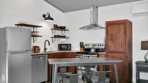 Une cuisine compacte équipée d’un réfrigérateur, d’un four à micro-ondes, d’une cuisinière et de meubles de rangement en bois.