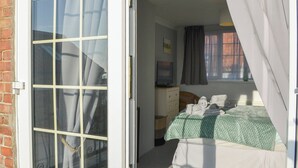 Un dormitorio con cama, cómoda, televisor y ventana con cortinas.
