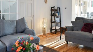 Una sala de estar con dos sofás grises, una mesa de centro con un florero y una estantería.