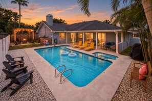 Ein Garten mit Pool, Liegestühlen und einer überdachten Terrasse.