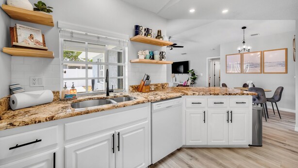 Una cocina moderna con armarios blancos, encimera de granito y lavavajillas integrado.