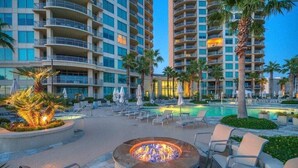 Un hôtel composé de plusieurs immeubles de grande hauteur, avec un espace piscine doté de chaises longues et un foyer extérieur.