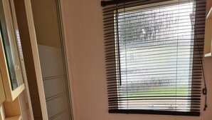 Ein Badezimmer mit Waschbecken, Toilette und einem Fenster mit Jalousien.