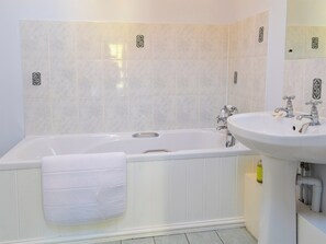 Un bagno moderno con una vasca freestanding, un lavabo su piedistallo e piastrelle decorative.