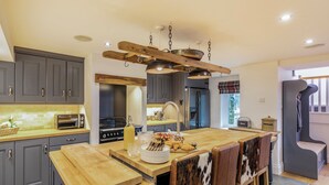 A modern kitchen with grey cabinets, a wooden island, and a hanging light fixture. - South Carolina Farm House (Matlock)
