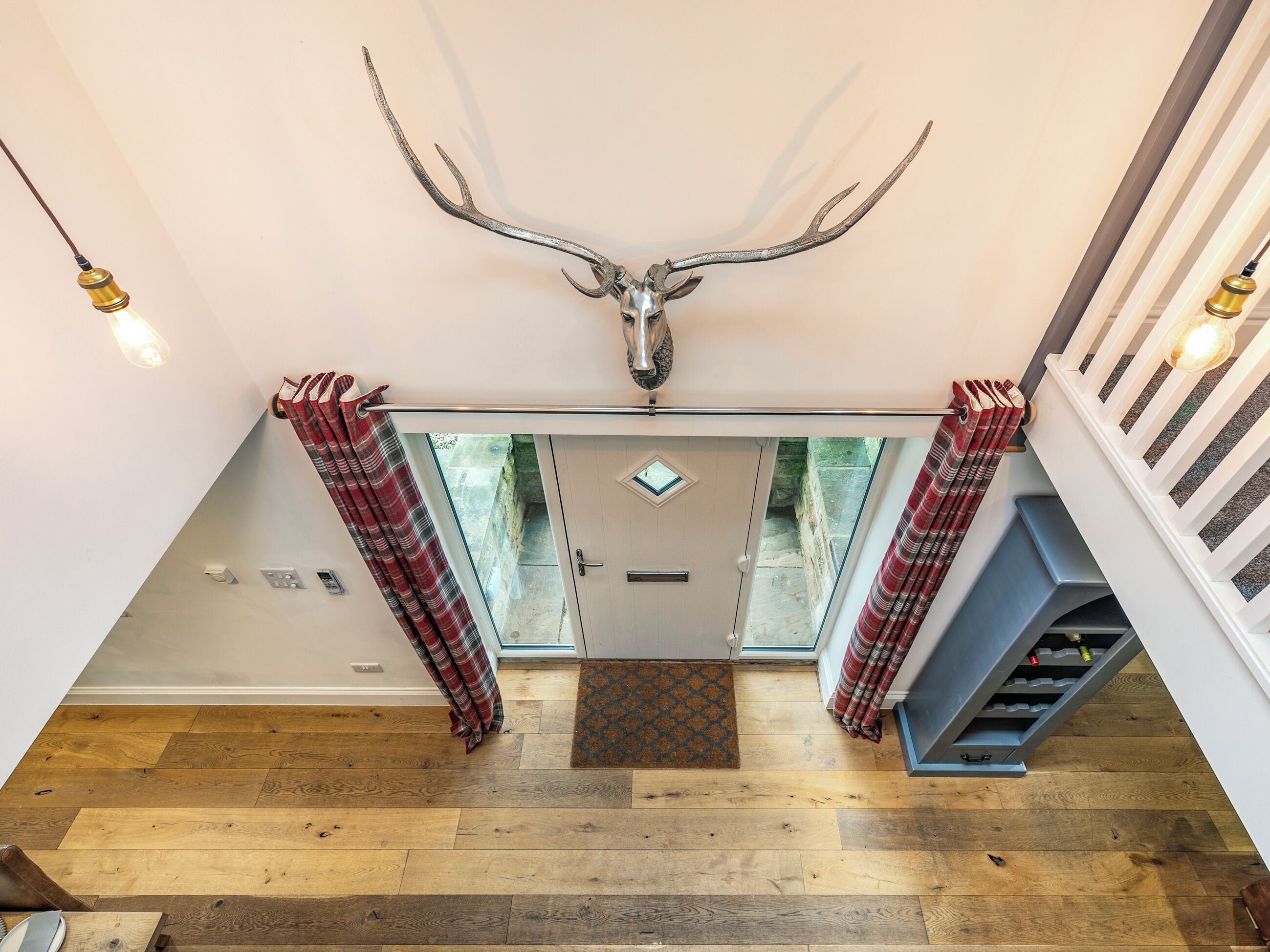 A staircase with a large antler mounted on the wall, wooden flooring, and a view of the outside.