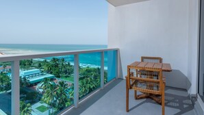 Un balcon avec vue sur l’océan et une chaise en bois.