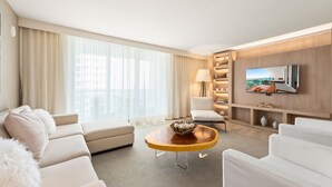 Une chambre d’hôtel moderne dotée d’une grande fenêtre, d’un téléviseur à écran plat, d’un canapé, d’une table basse et d’une lampe.