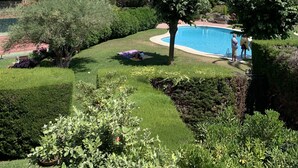 A swimming pool surrounded by well-maintained grass and trees, with a tennis court in the background. - Apartment in guarded residence overlooking swimming pool (Platja d'Aro)
