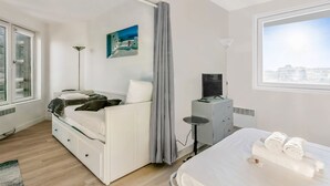 Un dormitorio moderno con cama, escritorio, silla, ventana y un cuadro en la pared.