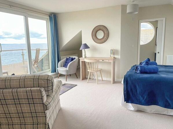 A bedroom with a bed, a desk, a chair, a sofa, and a view of the sea. - 5 bedroom accommodation in Hayling Island (Hayling Island)