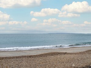 A beach with pebbles and calm sea under a partly cloudy sky. - 5 bedroom accommodation in Hayling Island (Hayling Island)