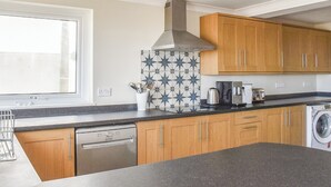 Una cocina moderna con armarios de madera, lavavajillas, cafetera y lavadora.