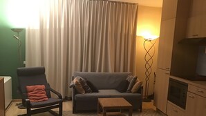 A compact living space with a sofa, a chair, a small table, and a kitchenette. - Cozy apartmen in center Sablon (Bruxelles)