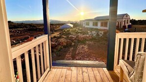 A wooden deck with a view of a house and landscape. - The Roadrunner: Experience Arizona Agritourism (Kingman)